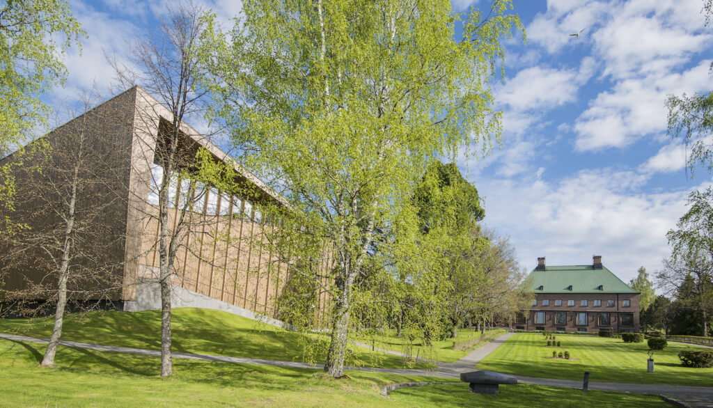 Edessä moderni museorakennus, takana vanha rakennus.