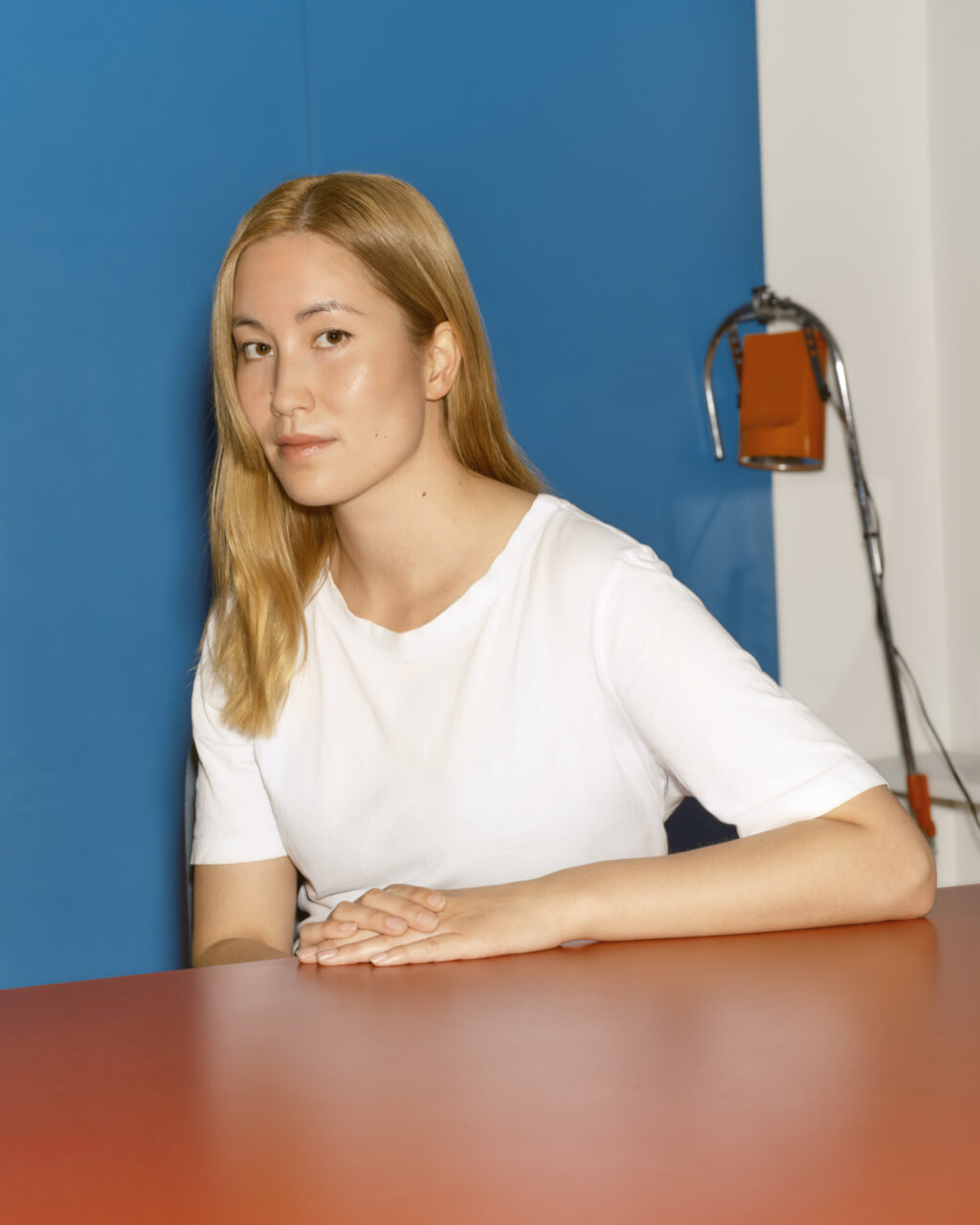 Young woman leaning on a red table.