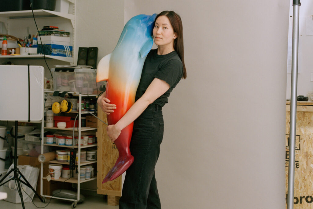 A younglady is holding a delfin sculpture in her lap.
