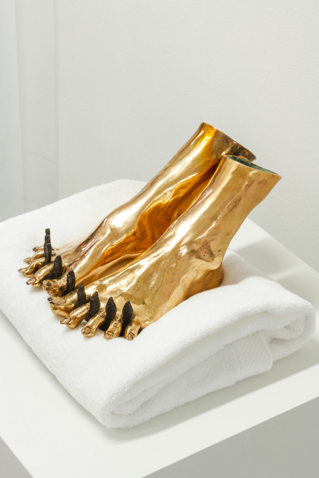 Feet cast in bronze on a towel.