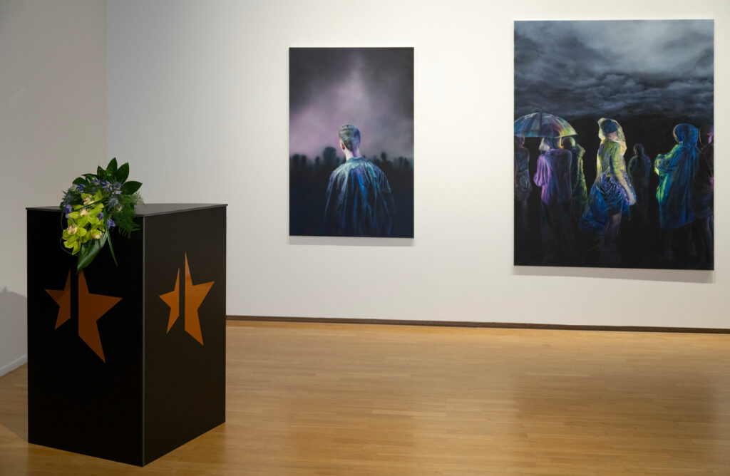 Näyttelytila, jossa seinällä kaksi maalausta.