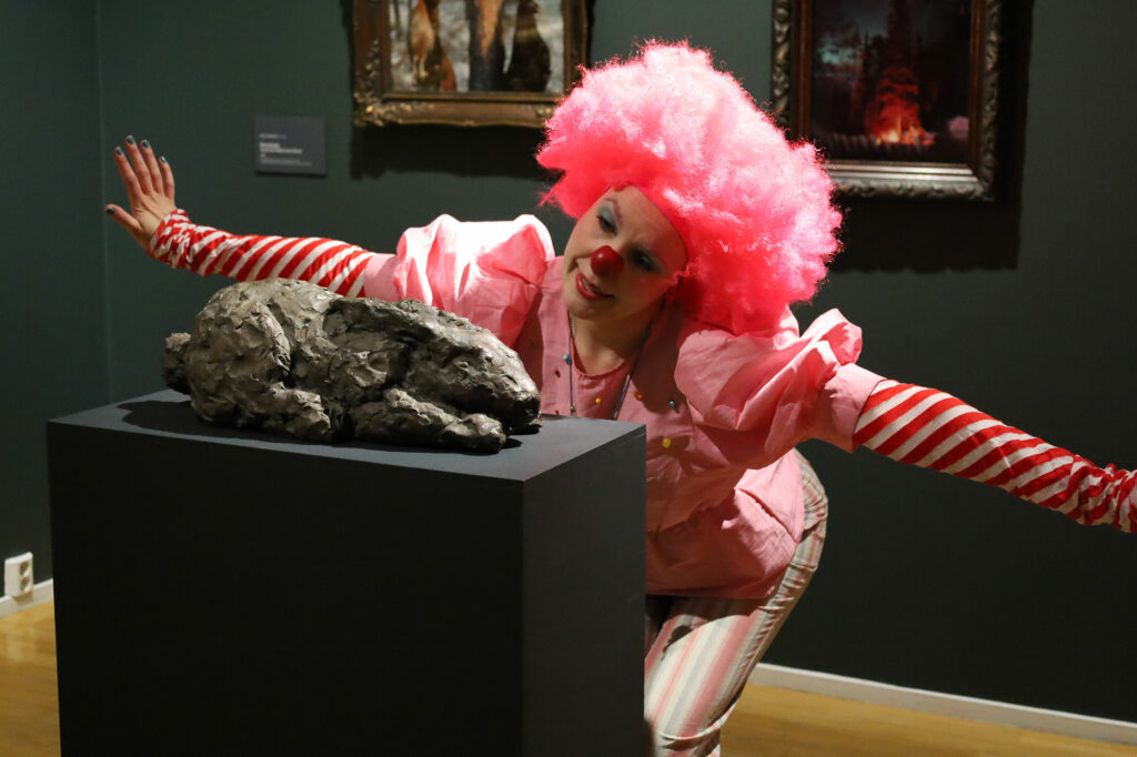 Pinkkitukkainen klovni tutkii jänistä esittävää veistosta.