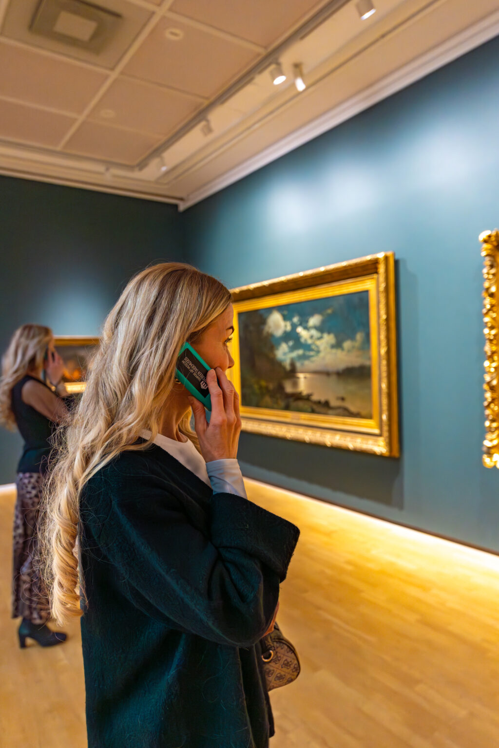 Nainen katsomassa taidetta pieni laite korvallaan.